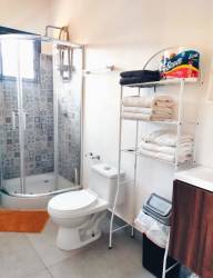 Contemporary bathroom with shower enclosure, patterned tiles, storage shelves, and window in Pedasi duplex
