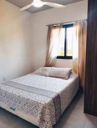 Simple bedroom with double bed, patterned linens, ceiling fan, and window with curtains in Pedasi duplex