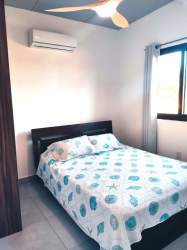 Master bedroom with bed, ceiling fan, air conditioner, and window in Pedasi duplex for sale