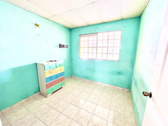 Exterior single story yellow house with barred windows and concrete patio at Brisas de Arraiján Panama Oeste