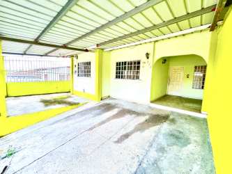 Covered carport area and patio entrance of yellow painted house for rent in Brisas de Arraiján Panama