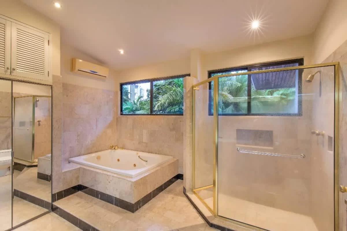 Modern bathroom with glass shower, skylight, and beige tiles in Obarrio duplex Panama