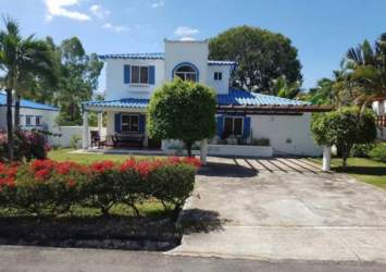 Two-story Mediterranean-style beach home with blue tile roof, lush garden, driveway and balcony in Playa Blanca