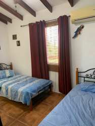 Bedroom with two single beds with blue bedding, tiled floor, floral curtains Playa Blanca house