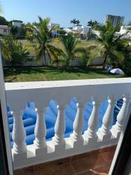 Bright living room with split AC, TV, reclining sofas, tiled floor, large windows and garden views in Playa Blanca