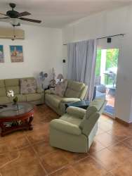 Contemporary living room with green sofas, ceiling fan, sliding door to patio in Playa Blanca beach residence
