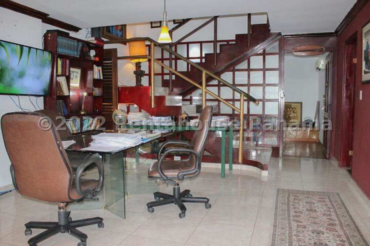 Traditional living room with wood shelves, stairs and study area in Los Ángeles house El Dorado Panama