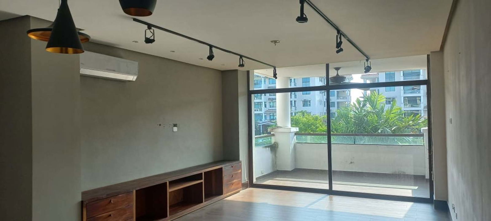 Bright living room with large glass doors opening to spacious balcony overlooking gardens in PH Costamare Panama