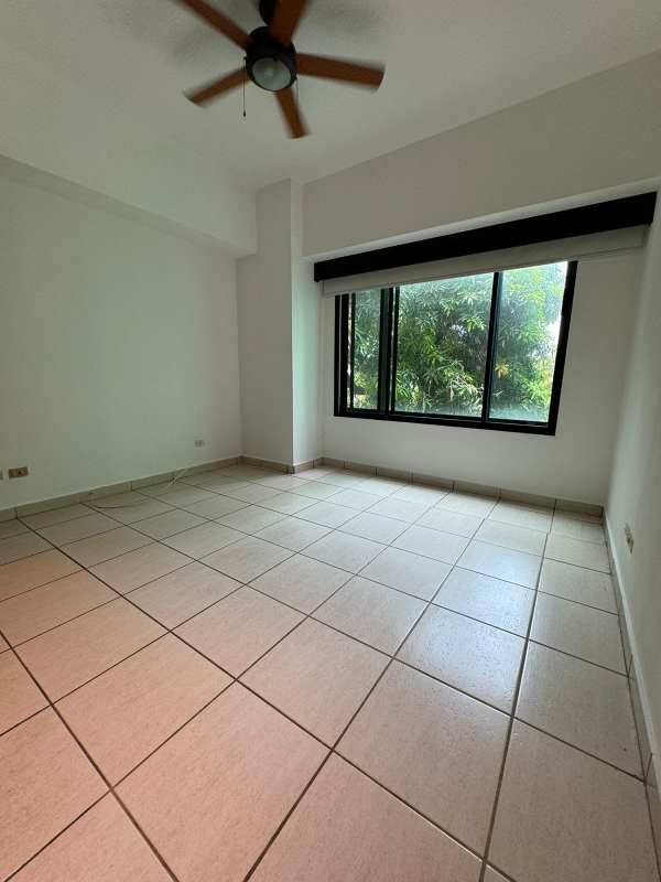Bedroom with large window, neutral colors, tile flooring in PH Green Pacific