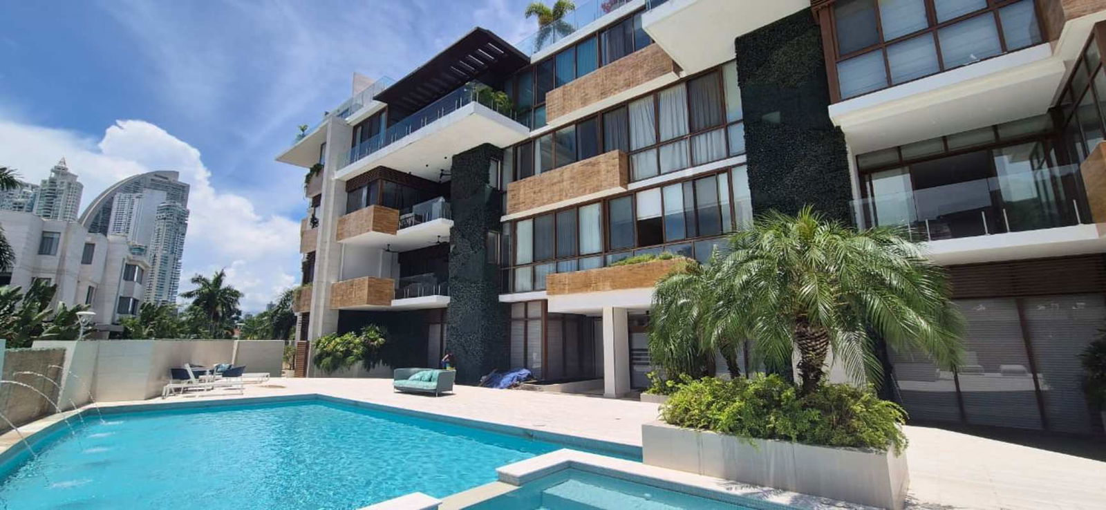 Modern oceanfront apartment building with balconies and landscaped pool in Panama.
