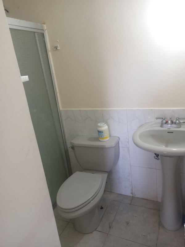 Small bathroom with pedestal sink, tiled walls and frosted shower enclosure Las Cumbres house Panama