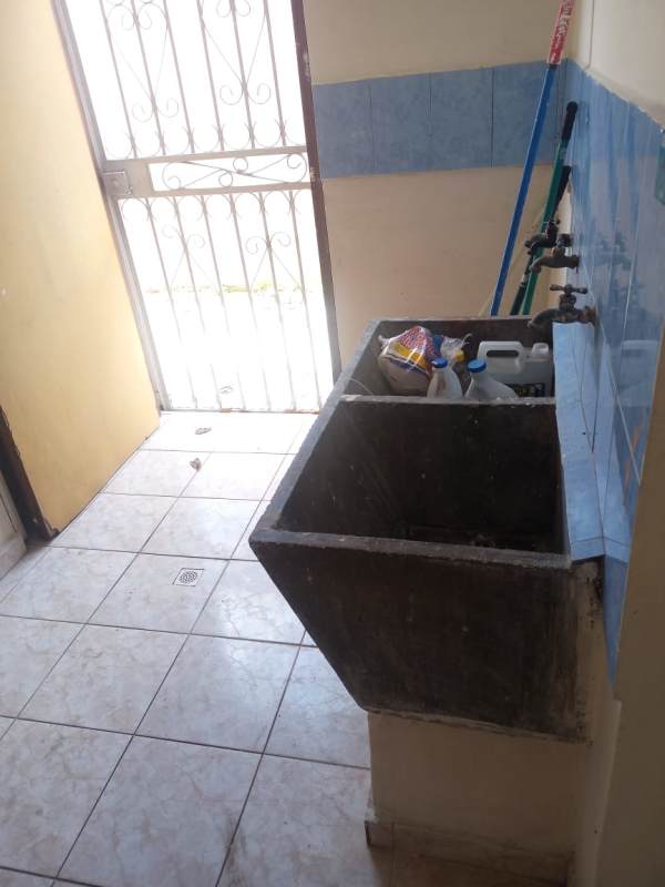 Laundry area with concrete sink, tiled walls and metal door in Las Cumbres Panama house