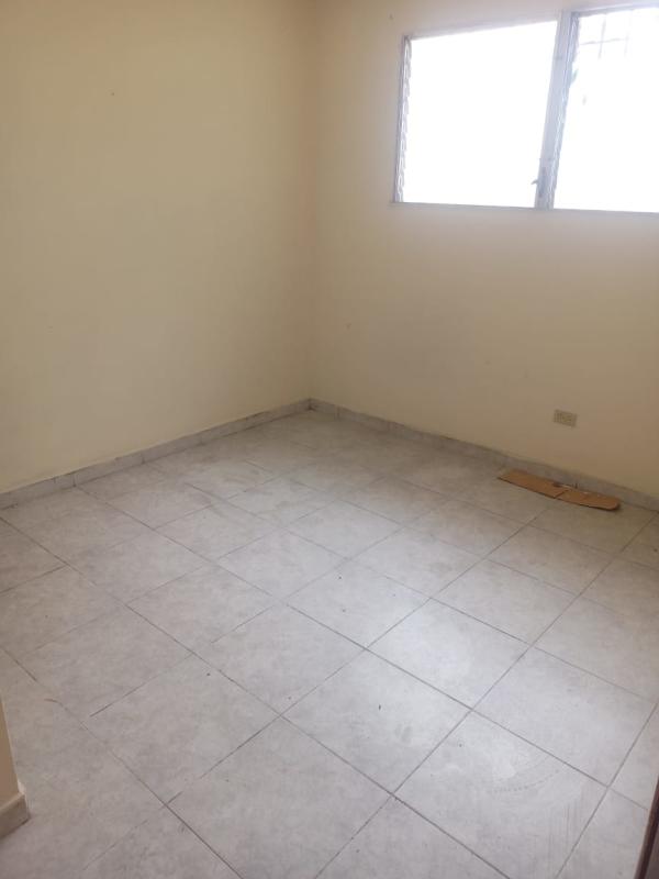 Bedroom with cream walls, tiled floor, window in Las Cumbres Panama house for sale