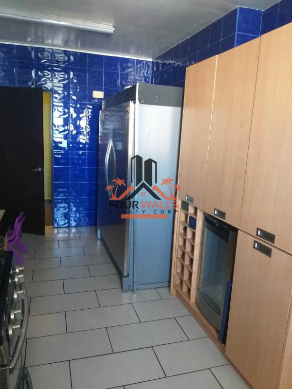 Kitchen with blue tiles, stainless fridge, oven and wooden cabinets in PH Pacific Coast