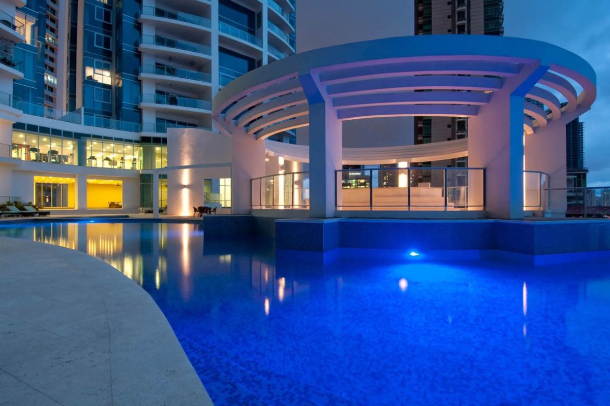 Modern high-rise exterior of Pacific Village with illuminated pool deck and pergola at night in Punta Pacifica