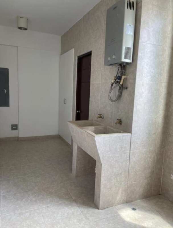 Laundry room equipped with utility sink, heater, cabinets inside Pacific Village apartment Punta Pacifica