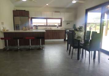 Open modern kitchen with island, bar stools, stainless appliances in Pedasí villa for sale