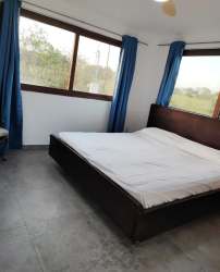 Bright bedroom with large windows, blue curtains and tiled floor in Pedasí home