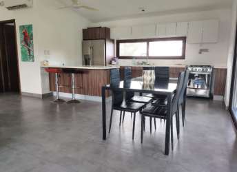 Modern kitchen dining space with wood cabinetry, granite counters, and large windows in Pedasí Panama