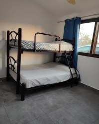 Minimalistic bedroom with bunk bed, large window, and blue curtains in villa Pedasí Panama