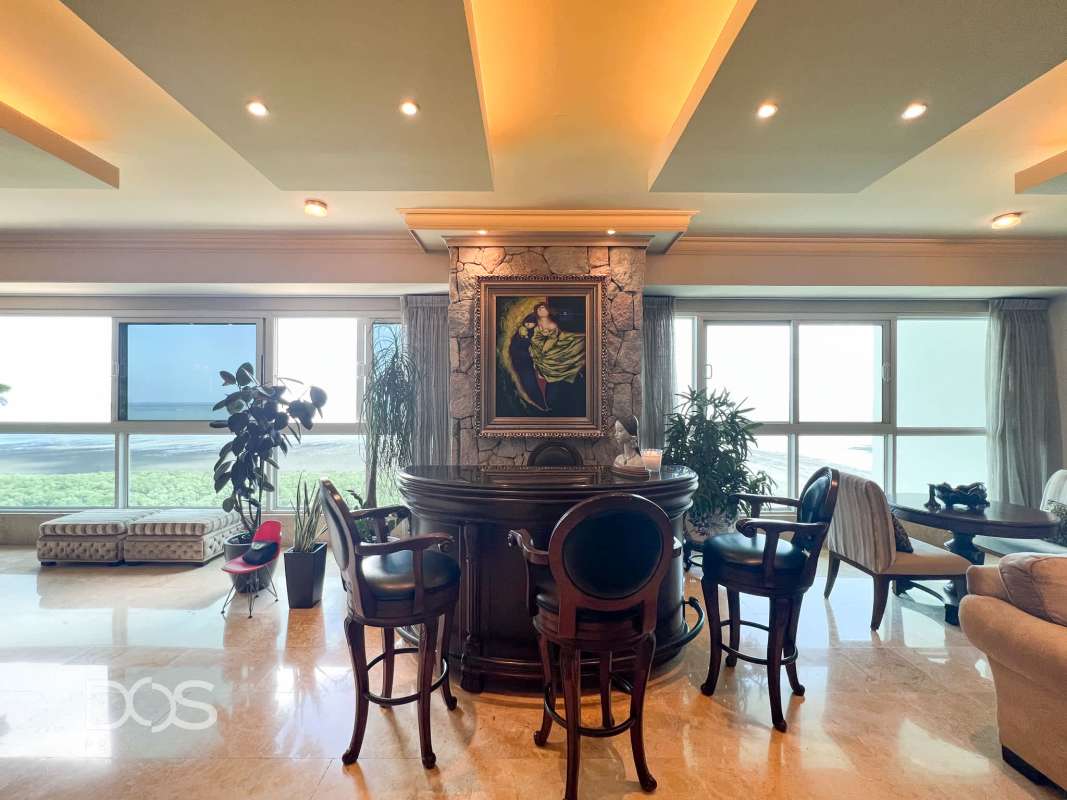 Modern living with floor-to-ceiling ocean view windows, marble floors, bar area in PH Torre Zeus Panama