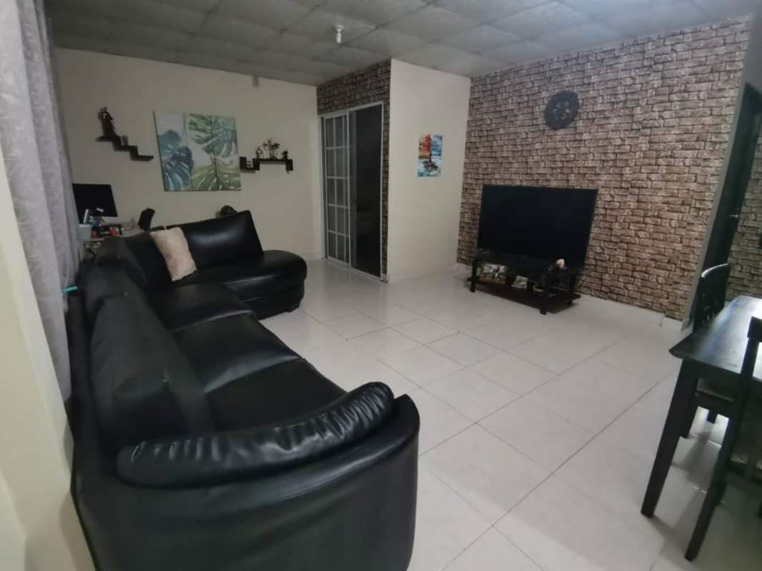 Living room with brick accent wall, TV, sofa set and tiled flooring in apartment Las Acacias Panama