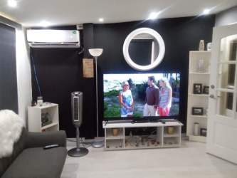 Spacious living room with TV, AC unit and modern furniture in Arboleda Panama Oeste house