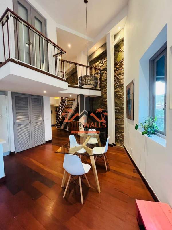 Dining space with stone wall, loft balcony and glass table in PH Jeronimo Casco Viejo Panama City
