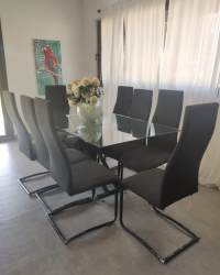 Dining room with glass table black chairs large window traditional decor in Pedasi villa Panama