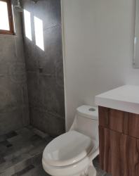 Bathroom with gray tiles, walk-in shower and wooden vanity in Pedasí Oasis Residences Panama