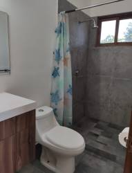 Bathroom with gray tiled walk-in shower, blue curtain, modern vanity in Pedasí Oasis Panama