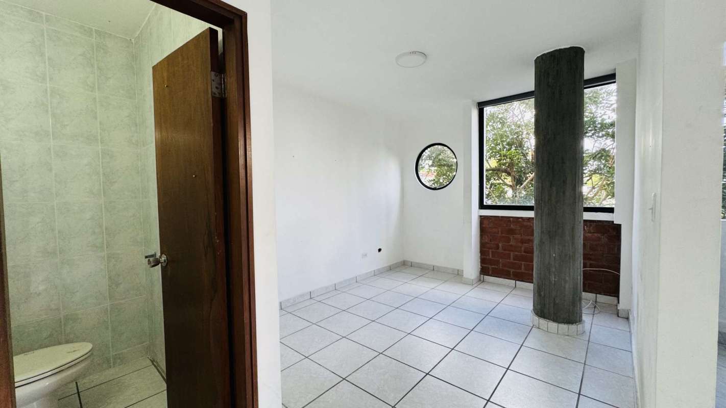Bedroom with round window, pillar, white walls and attached bath in PH Torre Altamira San Francisco Panama