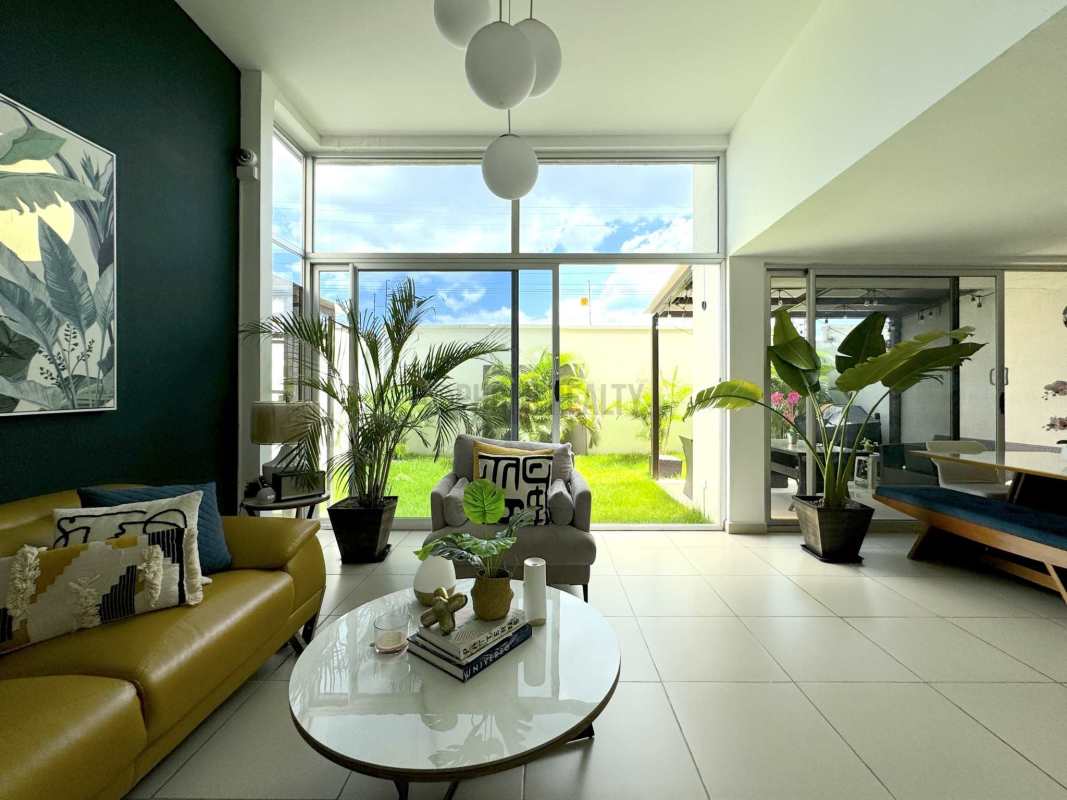 Modern living and dining room with large windows and indoor plants Costa Sur Village