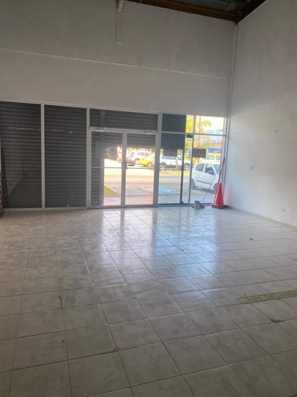 Empty commercial retail space with large glass windows tiled floors high ceilings facing parking Panama City