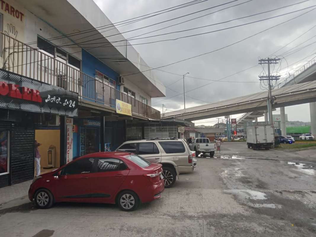 Wide view of two-story commercial plaza with storefronts, signage and parking spaces near highway in 24 de Diciembre Panama