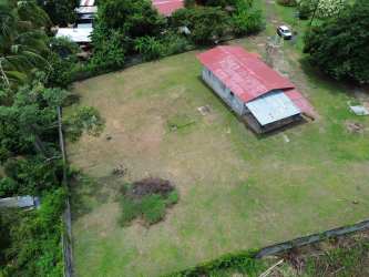 Aerial image of fenced corner property with small house and greenery in Panama Oeste