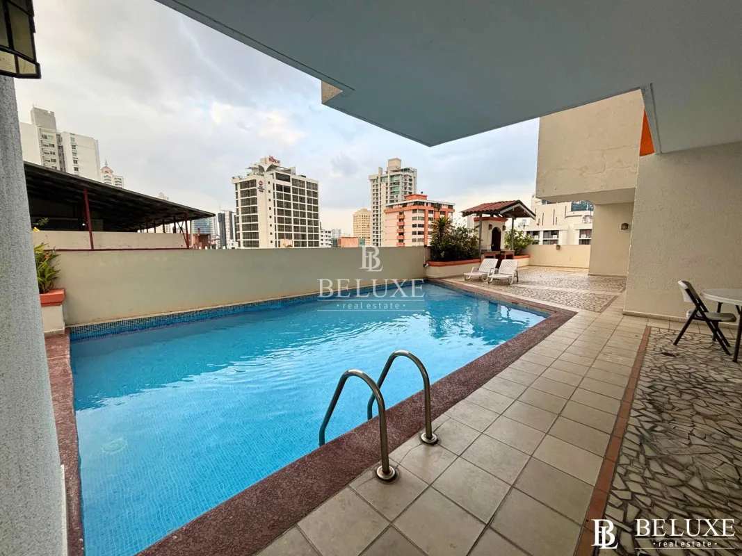 Spacious living room with white sectional sofa, wooden furniture, balcony access with city view in PH El Cangrejo Panama