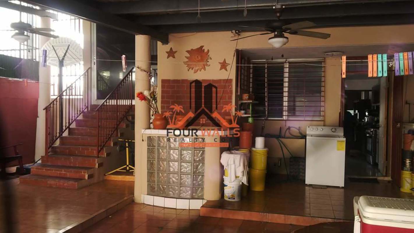 Covered tiled terrace with ceiling fans, dining setup and garden view in Villa de las Fuentes house Panama