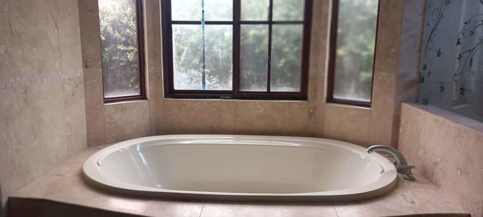 Kitchen with dark cabinetry, granite countertops, island counter, large window in Sunset Coast home Panama City