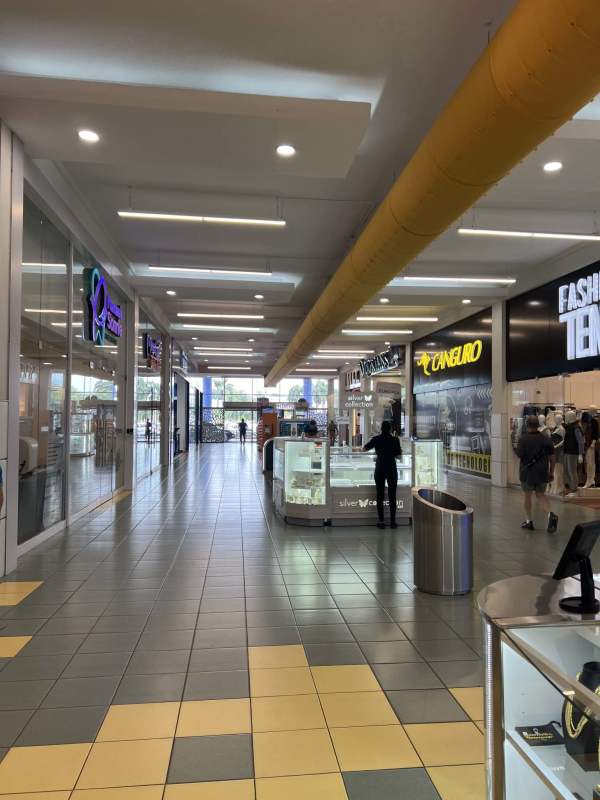 Wide corridor with multiple store entrances and tiled floors inside Albrook Mall Panama City