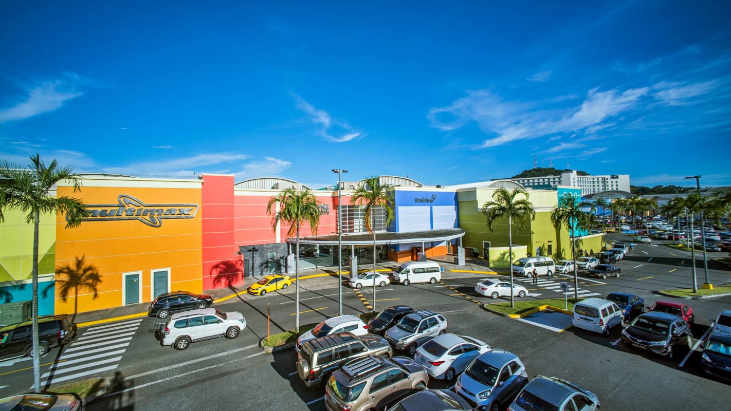 Colorful exterior of Albrook Mall Panama with parking lot and palm trees