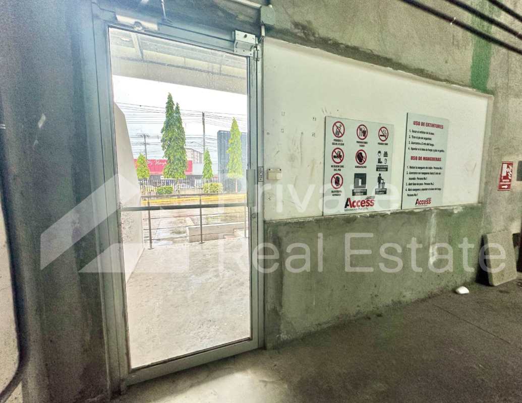 Warehouse exit area with glass door, concrete walls, safety signage in Tocumen Storage Complex