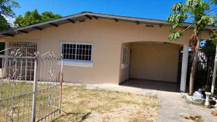 Single-floor beige house with metal gate, arched carport and front yard Las Tablas Panama