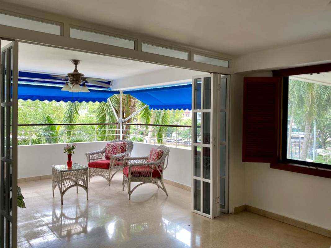 Bright enclosed balcony sunroom with wicker furniture in PH Bella Vista Park Panama for rent