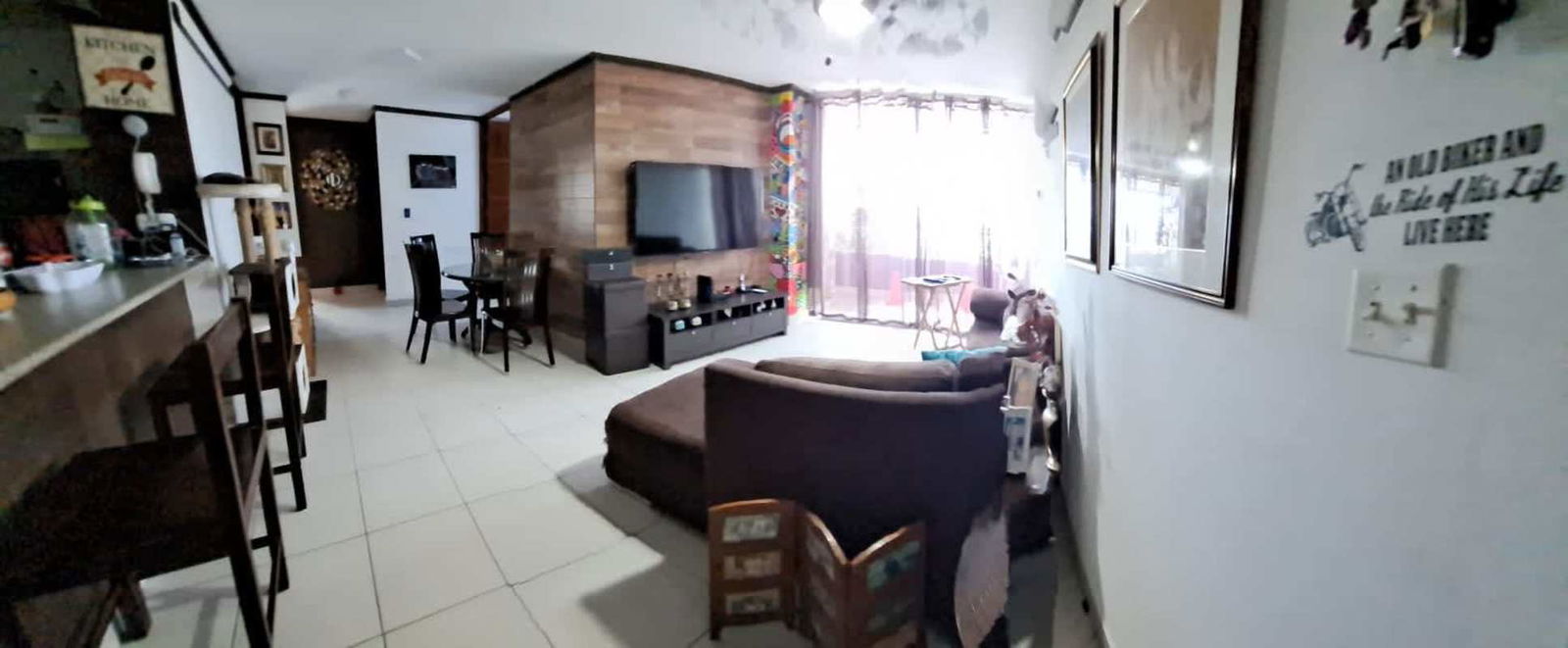 Living dining area with large window, wood accent wall, open kitchen PH Central Park Panama City Vía Transístmica