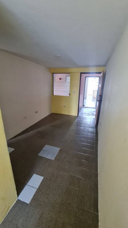 Minimalist open living area with tiled floors and kitchenette, yellow accent wall PH Morya Panama City