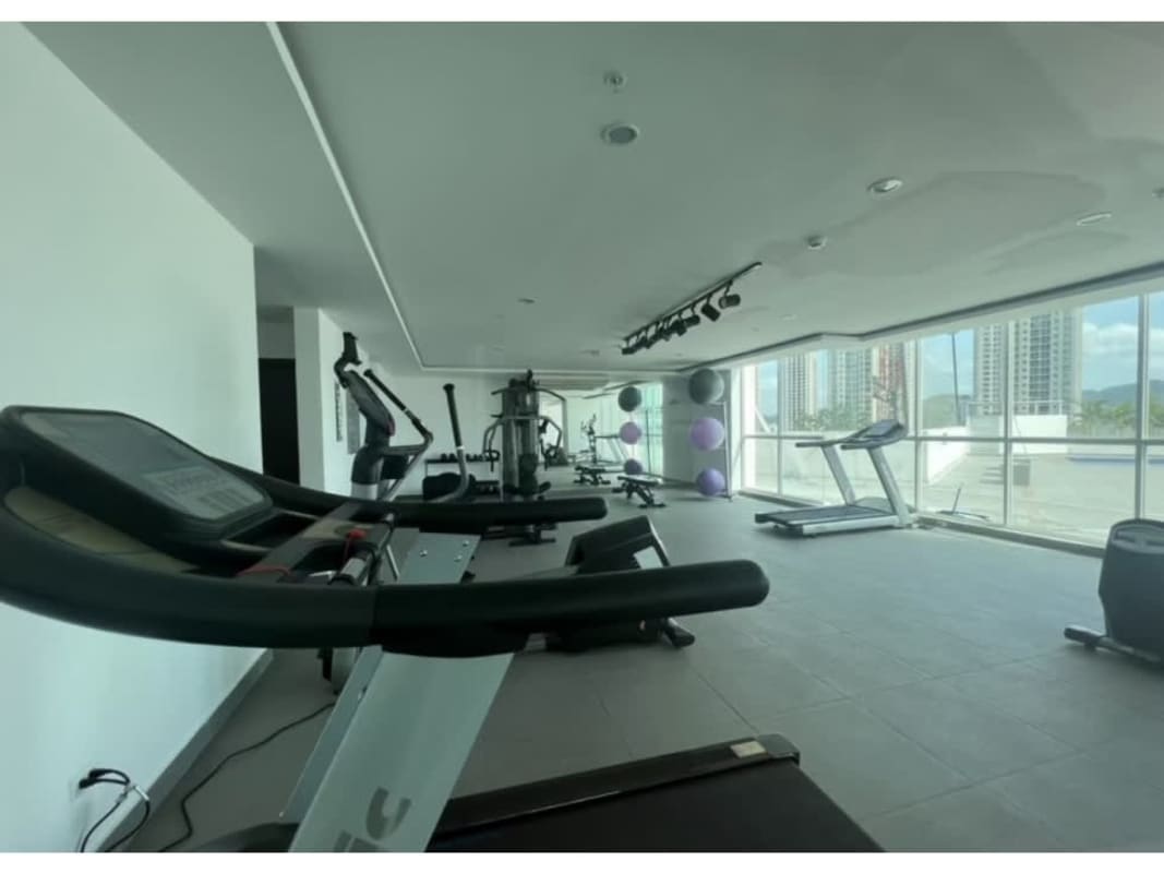 Modern fitness center with exercise equipment and large windows facing city view in PH Kings Park Condado del Rey Panama