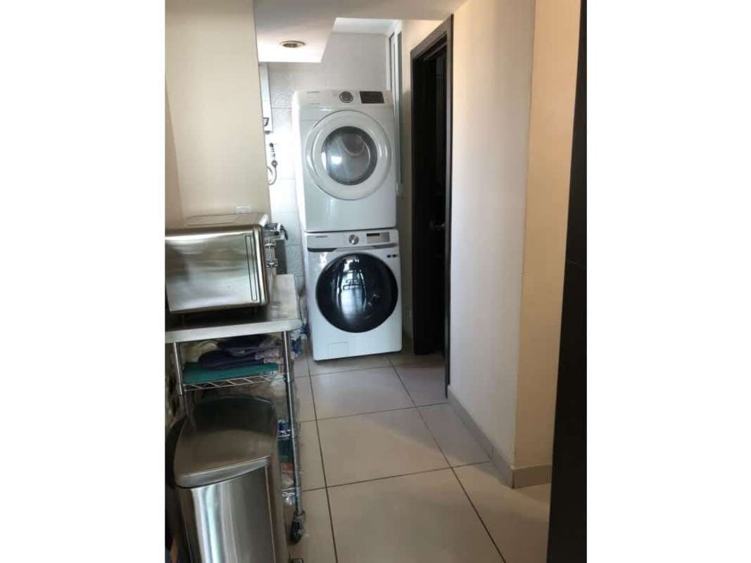 Laundry room with stacked washer and dryer, stainless countertop and microwave in PH Kings Park Condado del Rey Panama