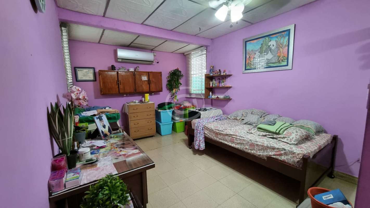 Bedroom with purple walls, ceiling fan, wooden storage in house for sale Tumba Muerto Panama City