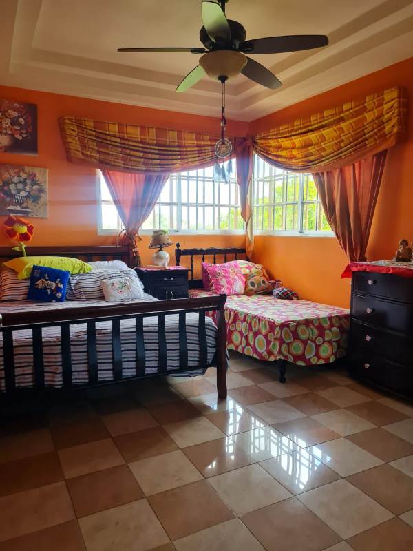 Bedroom with large windows, colorful walls, two beds and ceiling fan Altos de Santa María Panama